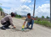 Bhabinkamtibmas Polsek Langsa dan Warga Gampong Alue Beurawe Gotong Royong Tambal Jalan Berlubang